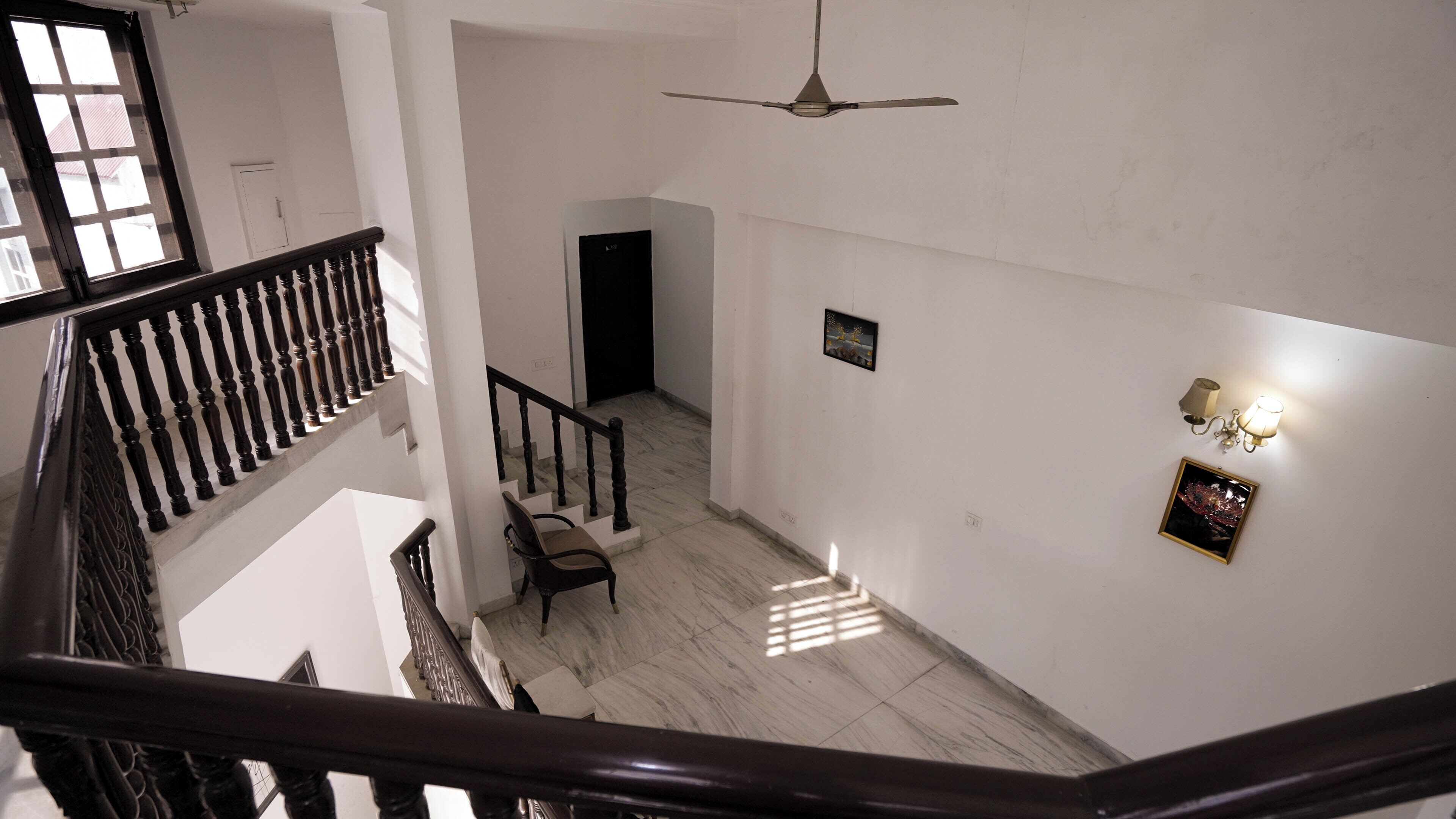 A multi-level interior with a staircase, a ceiling fan, and a chair in a hallway.