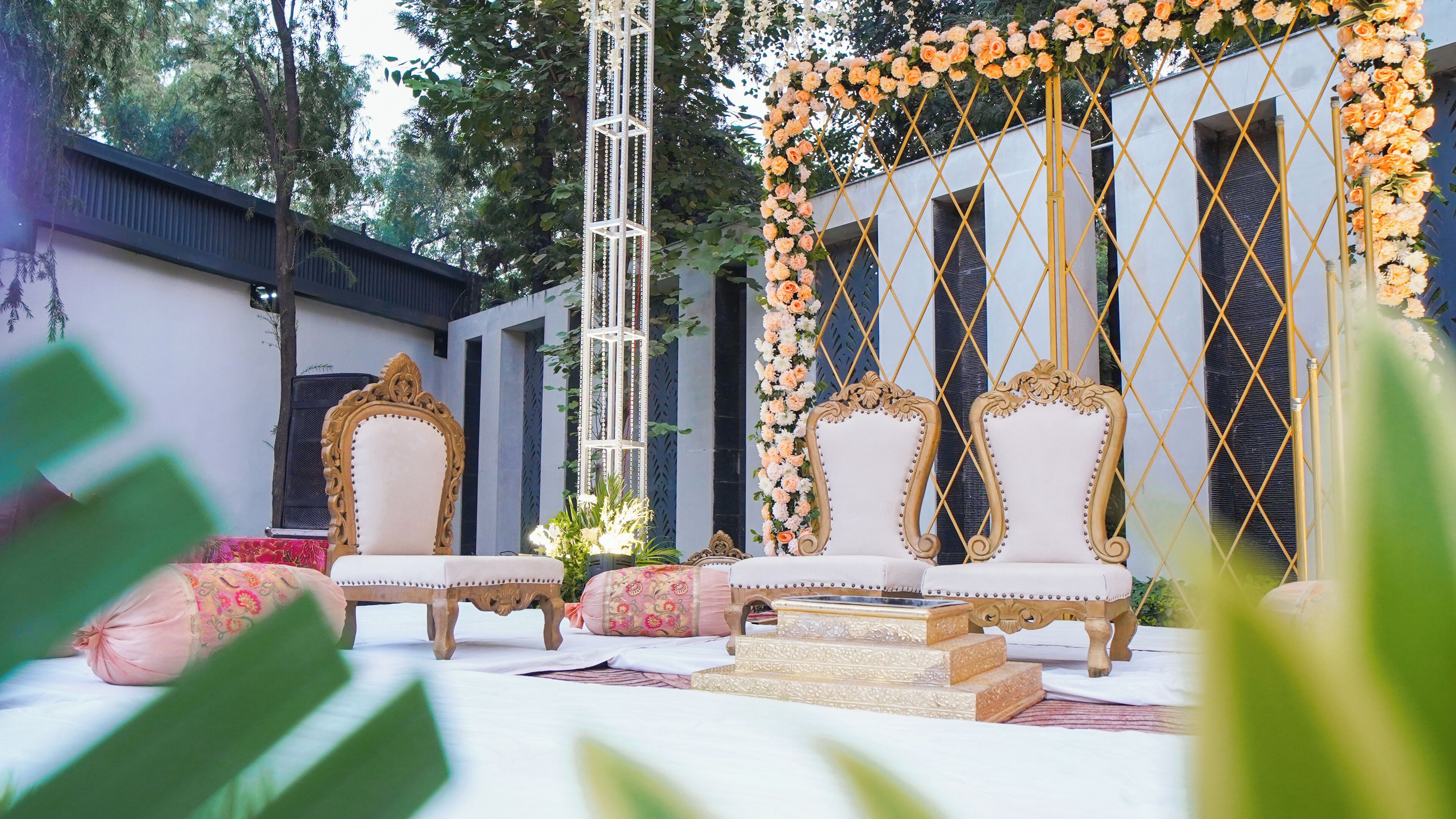 An outdoor seating area with ornate chairs and a floral backdrop.