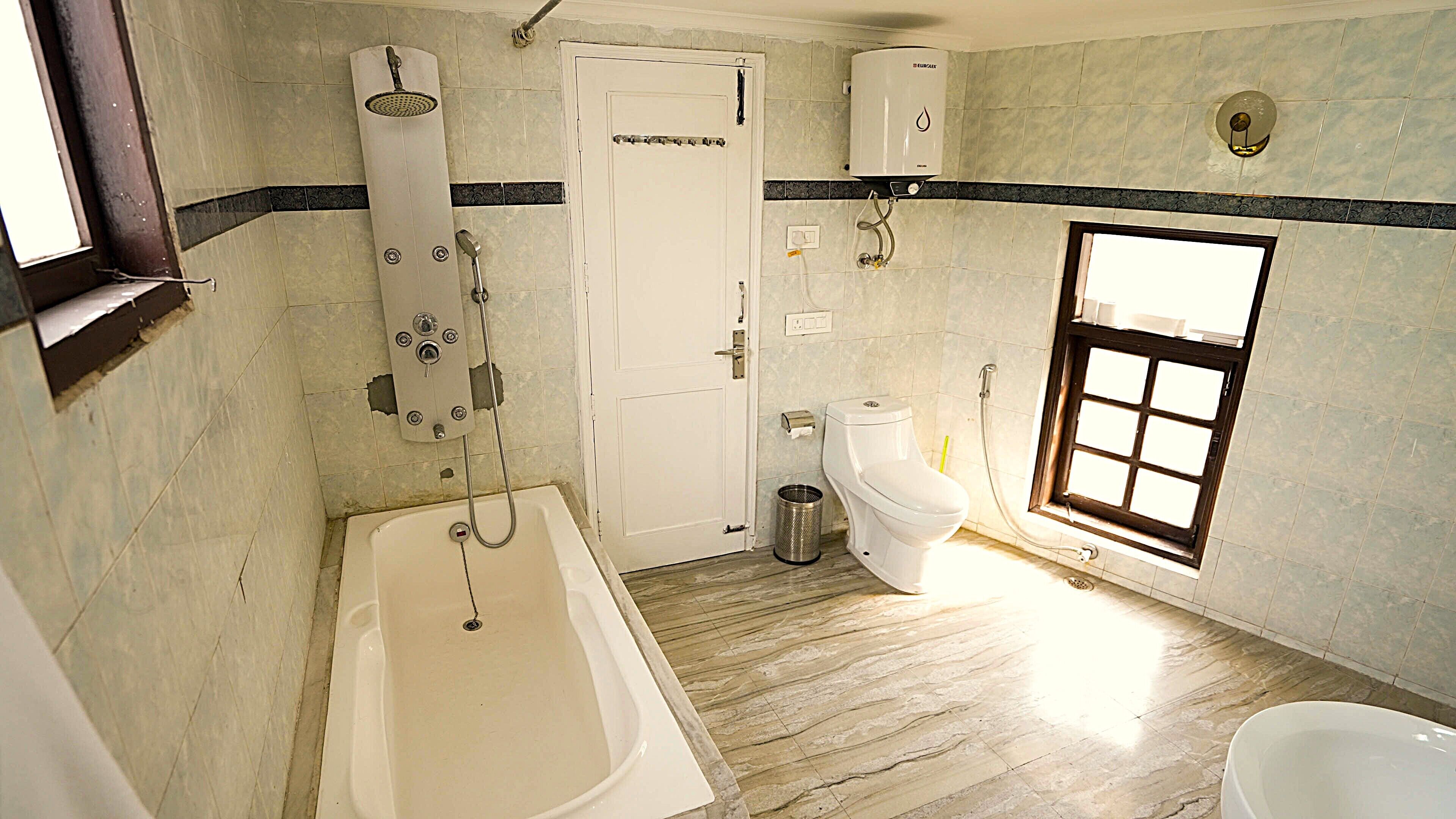 Ein Badezimmer mit Badewanne, Toilette, Dusche und einem Fenster.