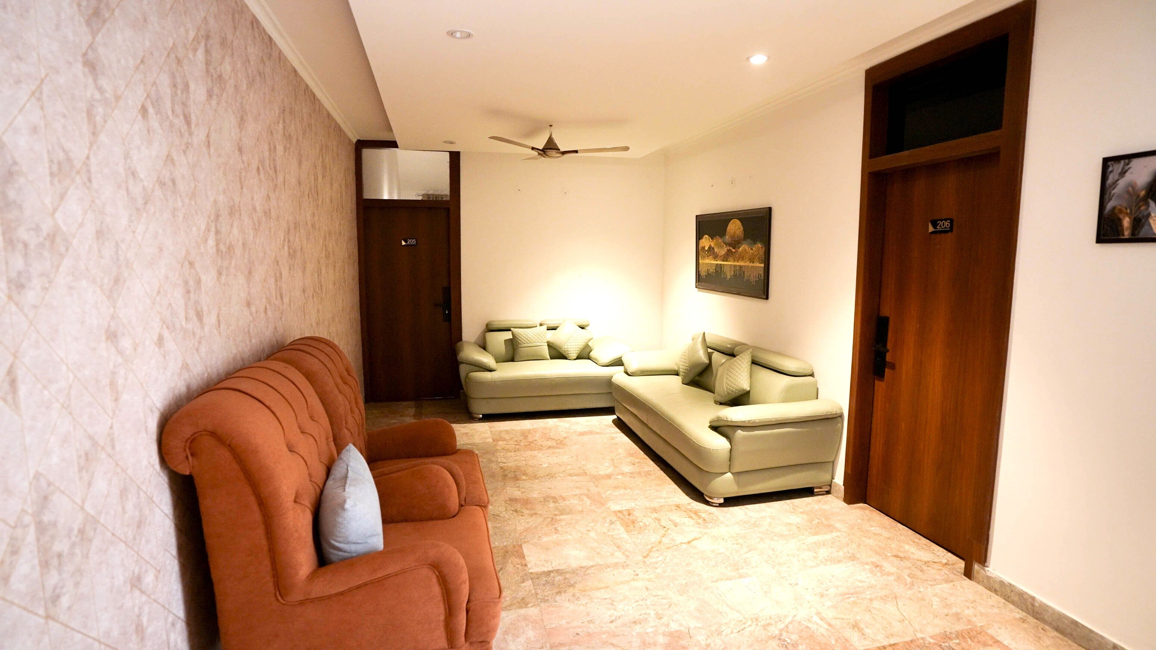 A hallway with a brown sofa, a beige sofa, and a ceiling fan.