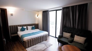 Une chambre d’hôtel moderne dotée d’un grand lit, d’un canapé, d’un plancher en bois et offrant une vue sur l’extérieur.