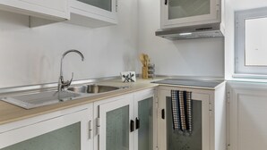 Una cucina con lavello in acciaio inossidabile, mobili bianchi e cappa aspirante integrata.