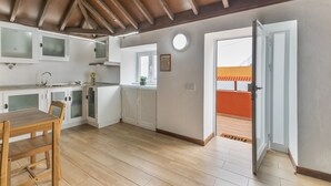 Cucina con mobili bianchi, tavolo da pranzo in legno e vista su un balcone esterno.