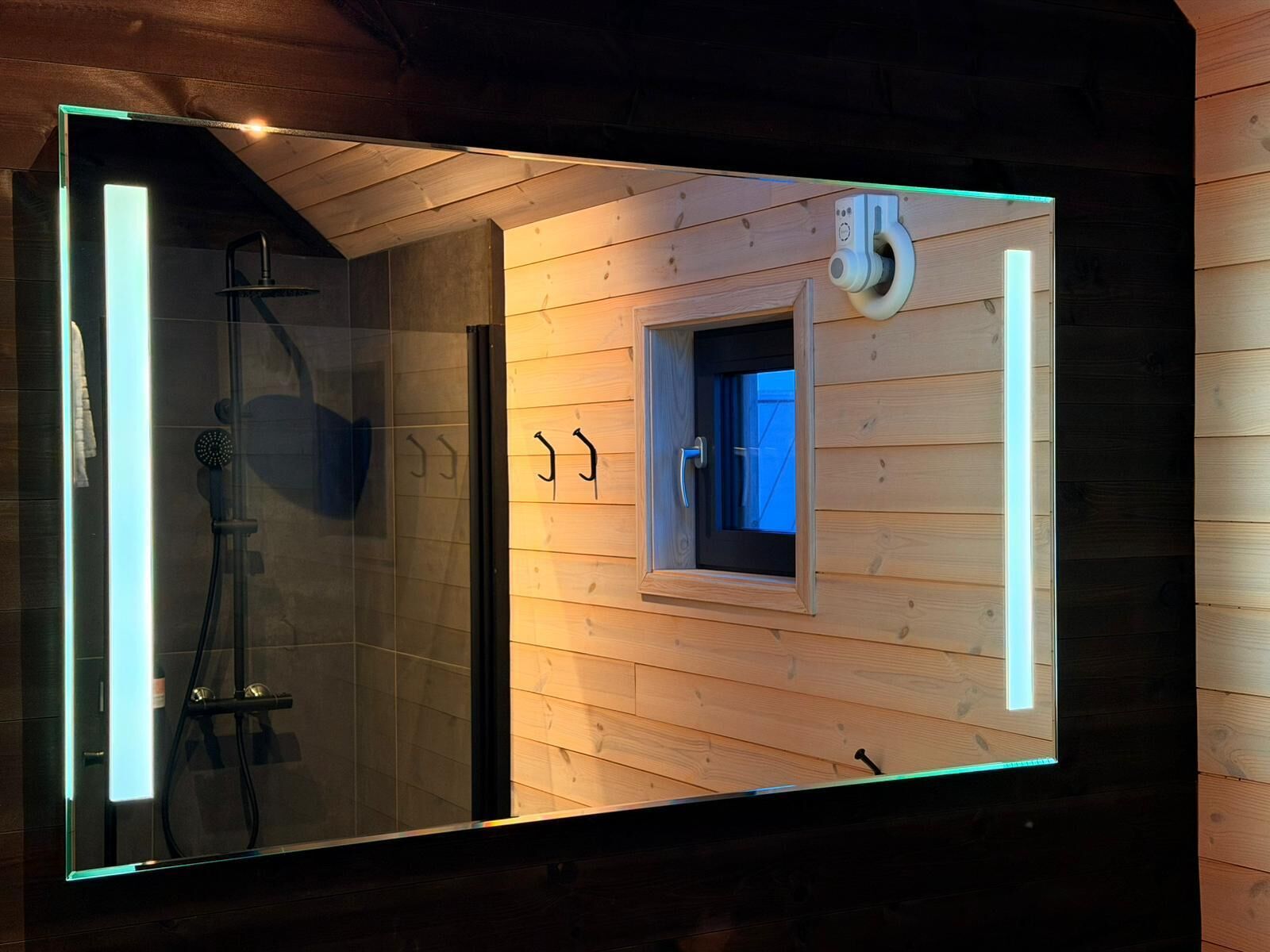 A modern bathroom with a glass enclosure, wooden paneling, a shower, and a small window.