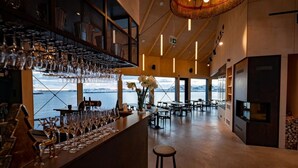 Un espace bar avec vue sur un lac, des meubles en bois et un luminaire suspendu.