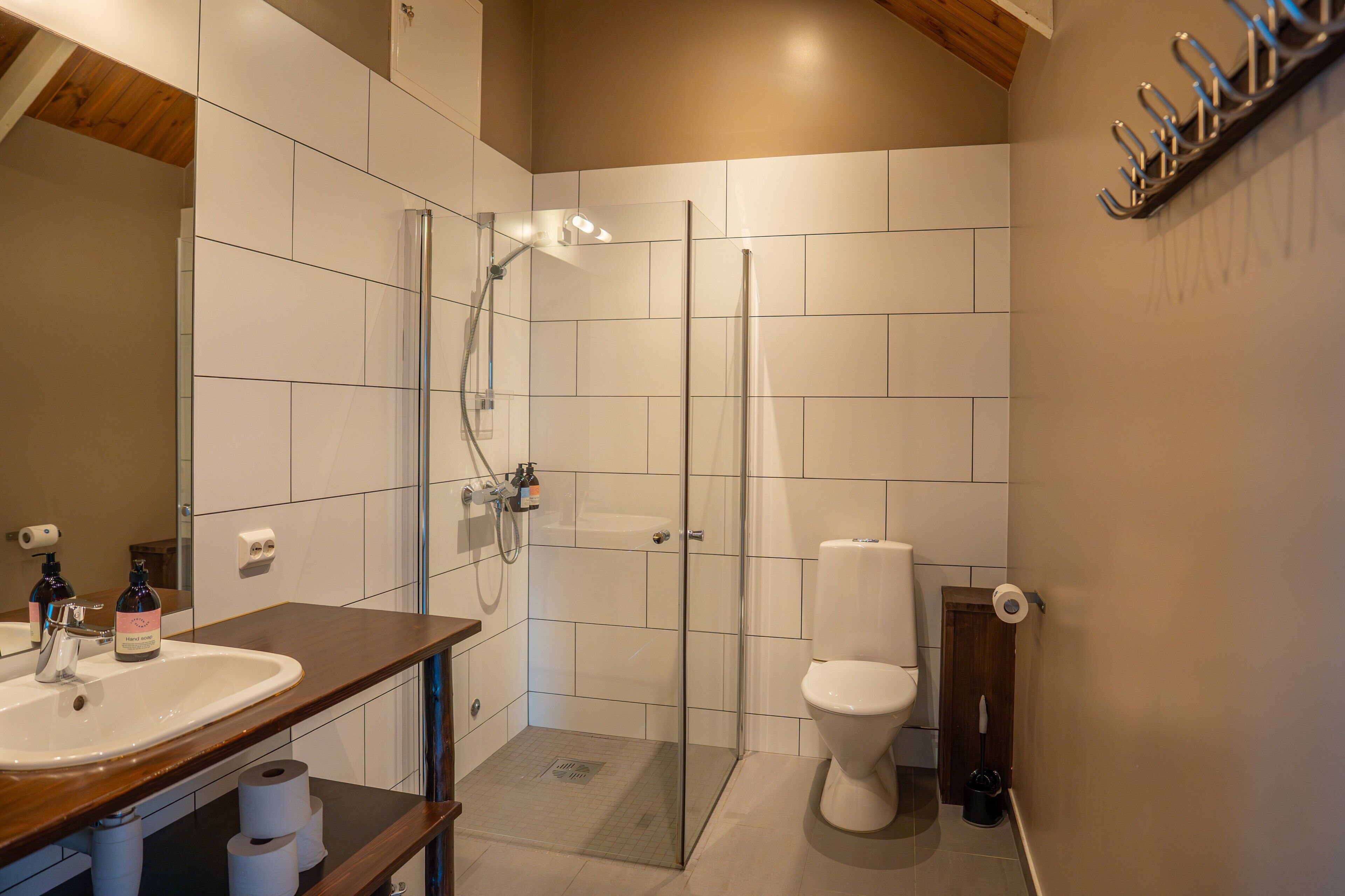 Une salle de bain moderne avec une douche à parois de verre, des toilettes blanches et un meuble-lavabo en bois avec un évier.