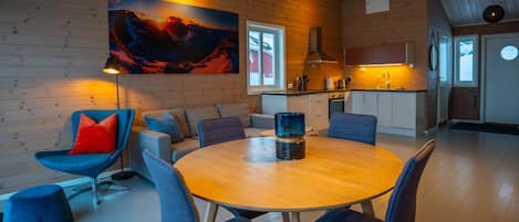 A modern interior with a wooden wall, a round dining table, and a sofa with blue chairs.