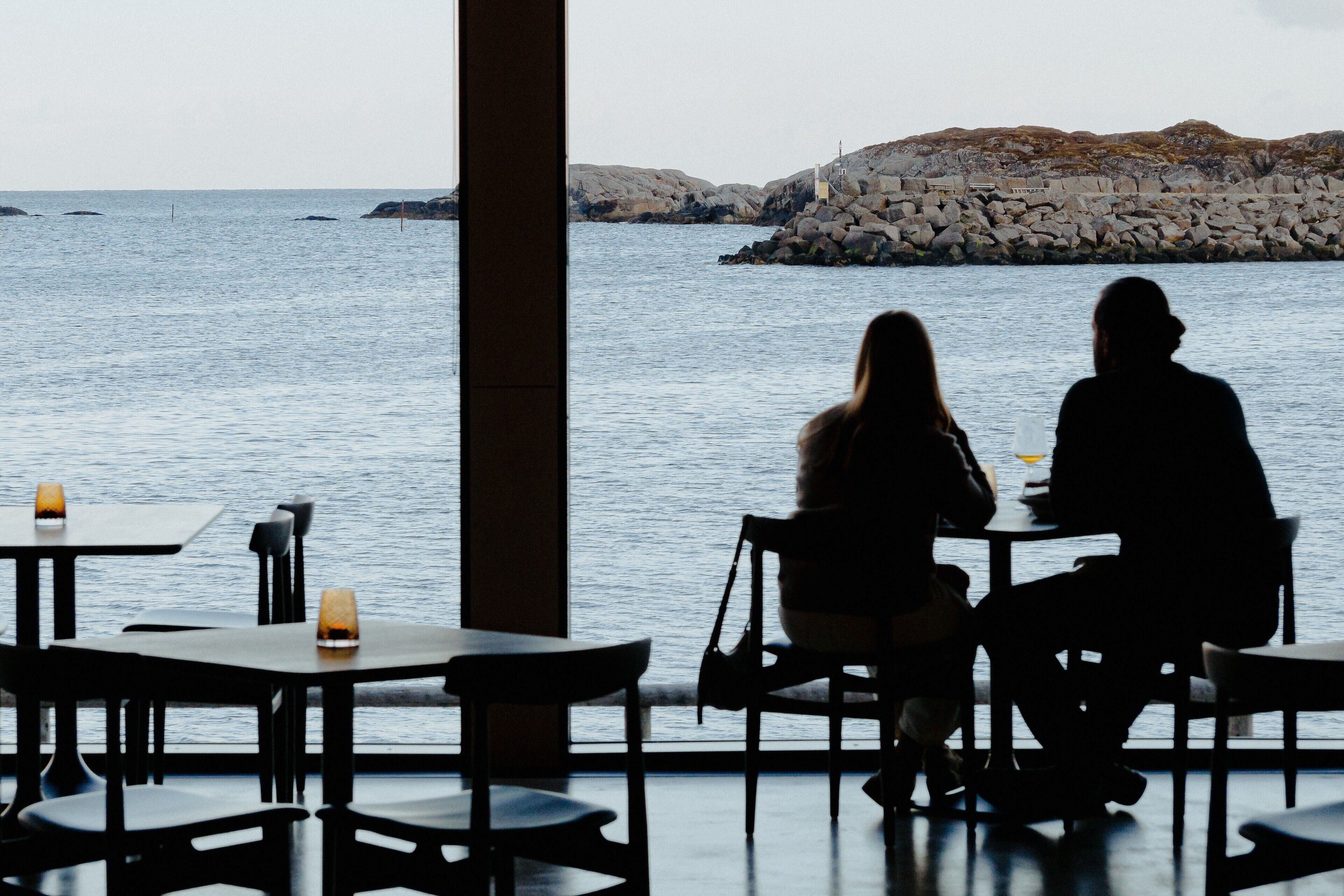 A restaurant with tables and chairs facing a rocky coastline.
