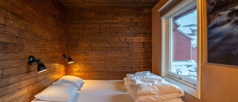 Et hyggeligt træsområde med en seng, et vindue og vægmonterede lamper.