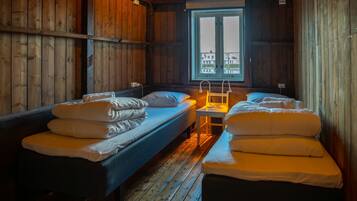 A cabin with two single beds, a small table, and a window with a view of buildings.