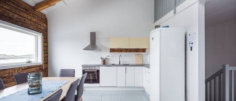 Una cocina compacta con armarios blancos, un horno empotrado y una campana extractora de acero inoxidable.