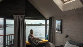 A room with a view of the water, a bench, a bed, and a skylight.