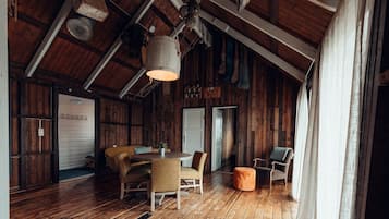 Um interior rústico de madeira com teto alto, uma mesa de jantar redonda e um espaço de estar acolhedor.