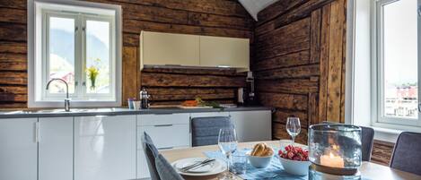 Ein Holzblockhaus-Interieur mit einem Esstisch für zwei Personen, einer Kerze und einer Obstschale.