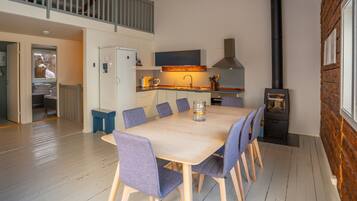A modern kitchen with a central island, a built-in stove, and a dining area with a large table and chairs.