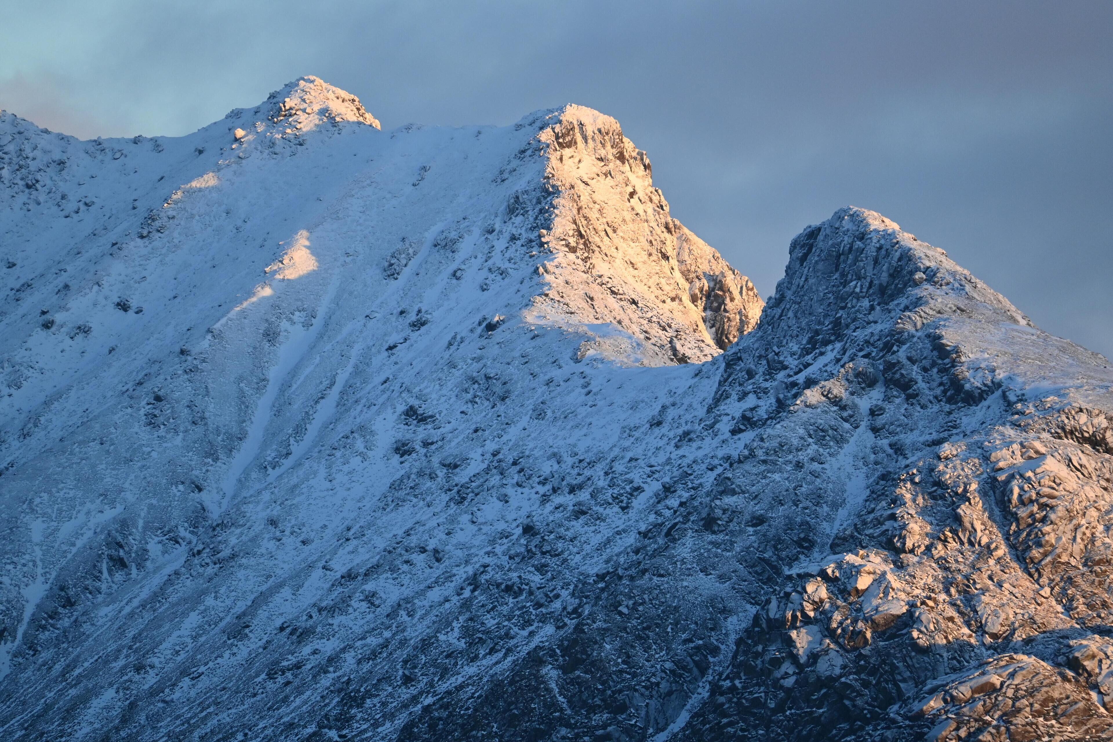 A snow-covered mountain with rugged terrain and rocky outcrops.