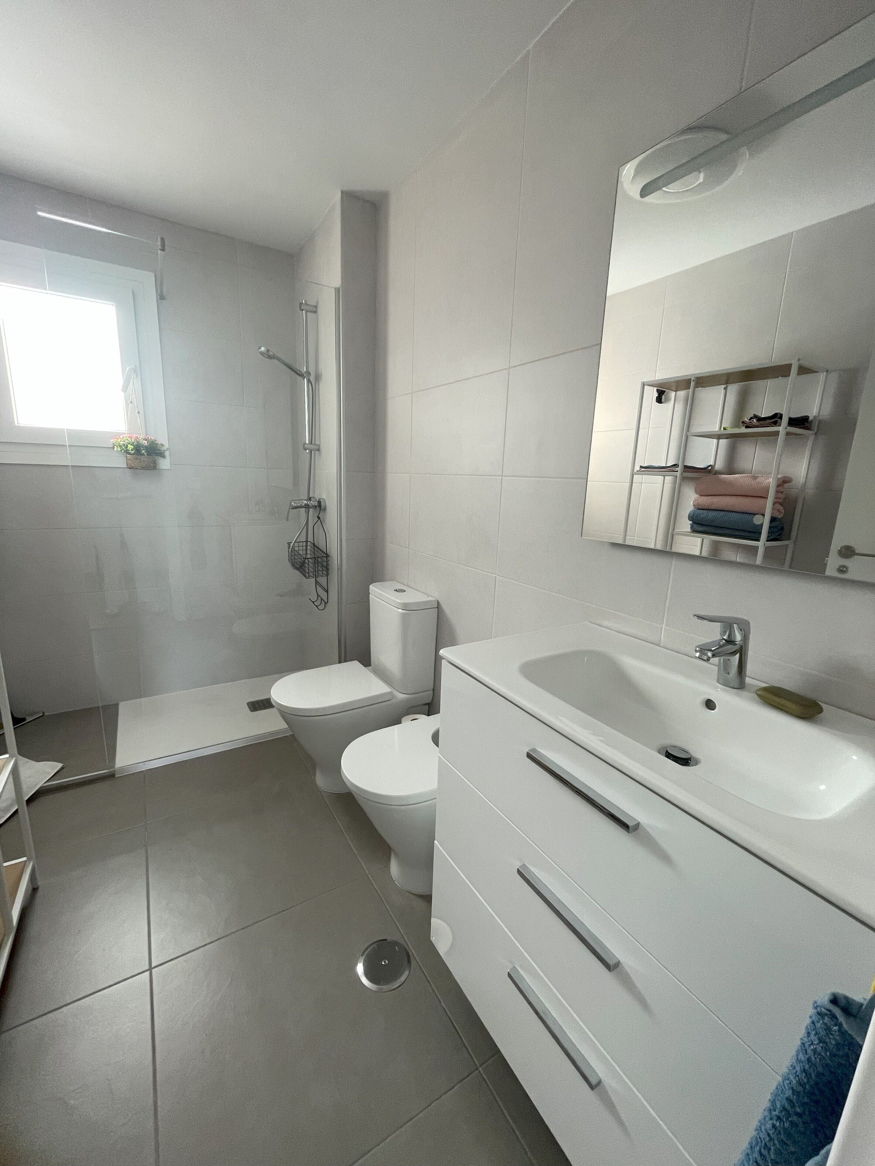 A modern bathroom with a shower, toilet, and sink.