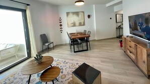 Ein modernes Wohnzimmer mit Essbereich, Fernseher und großem Fenster.