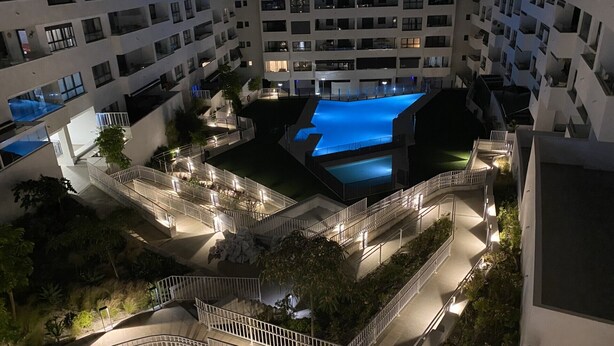 Ein mehrstöckiges Wohngebäude mit Innenhof, der einen Swimmingpool, Balkone und Treppenhäuser umfasst.