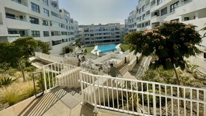 Ein moderner Wohnkomplex mit einem zentralen Schwimmbad, mehreren Balkonen und einer gepflegten Gartenanlage.