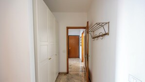 Un pasillo con una puerta blanca, una puerta de madera y un perchero metálico en la pared.