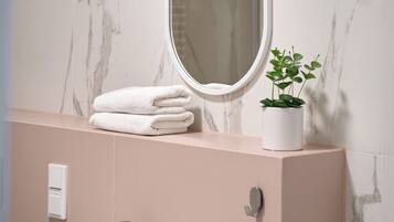 Une salle de bain avec un lavabo blanc, un miroir et une plante en pot.