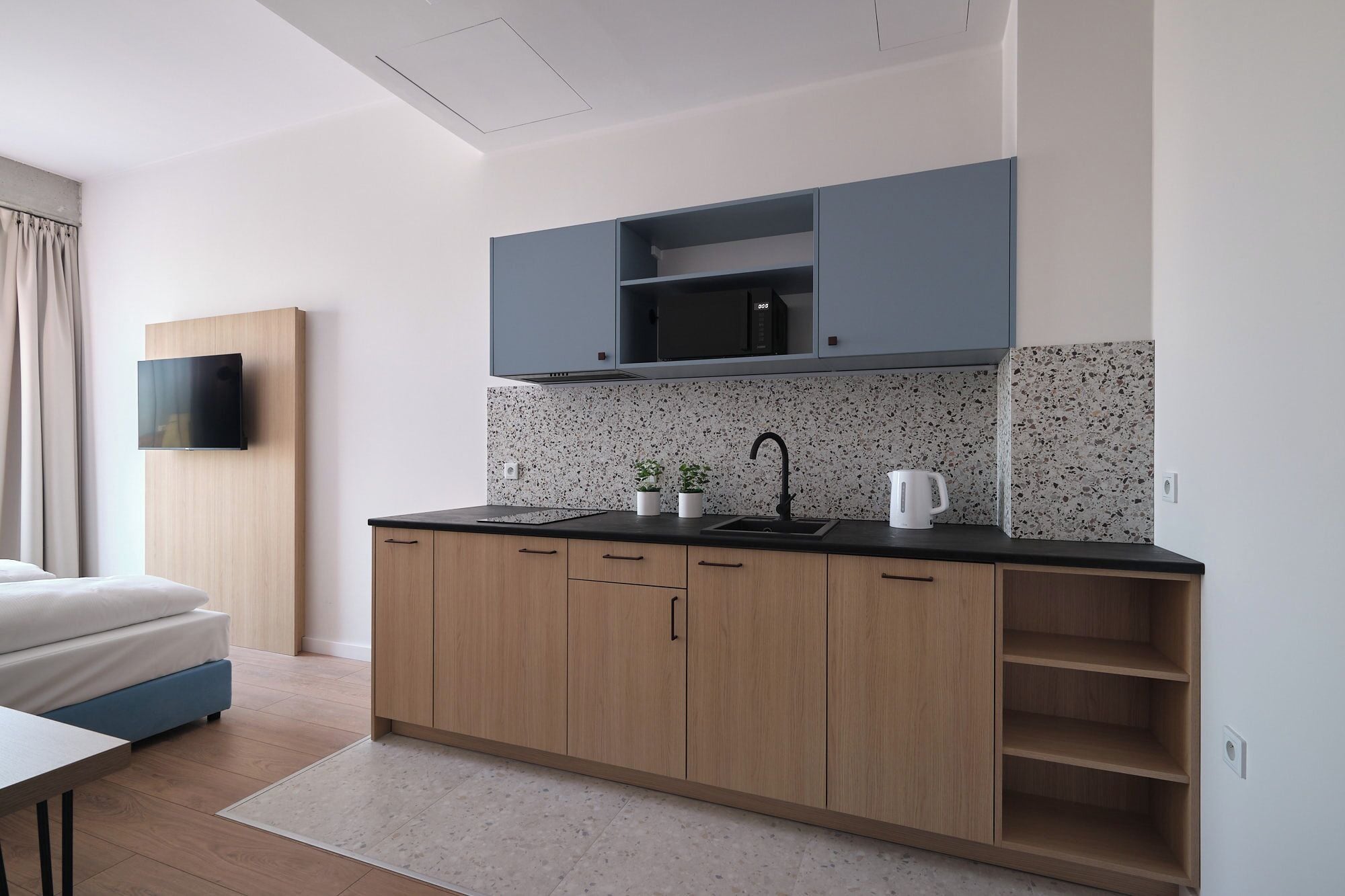 A modern kitchen with wooden cabinets, a black countertop, and a backsplash.