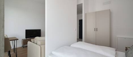 Una habitación de hotel moderna con una cama, televisor, sofá y armario.