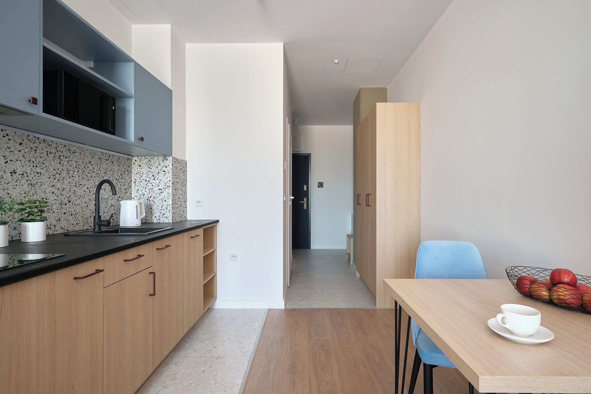 A modern kitchen with a black countertop, wooden cabinets, and a speckled backsplash.