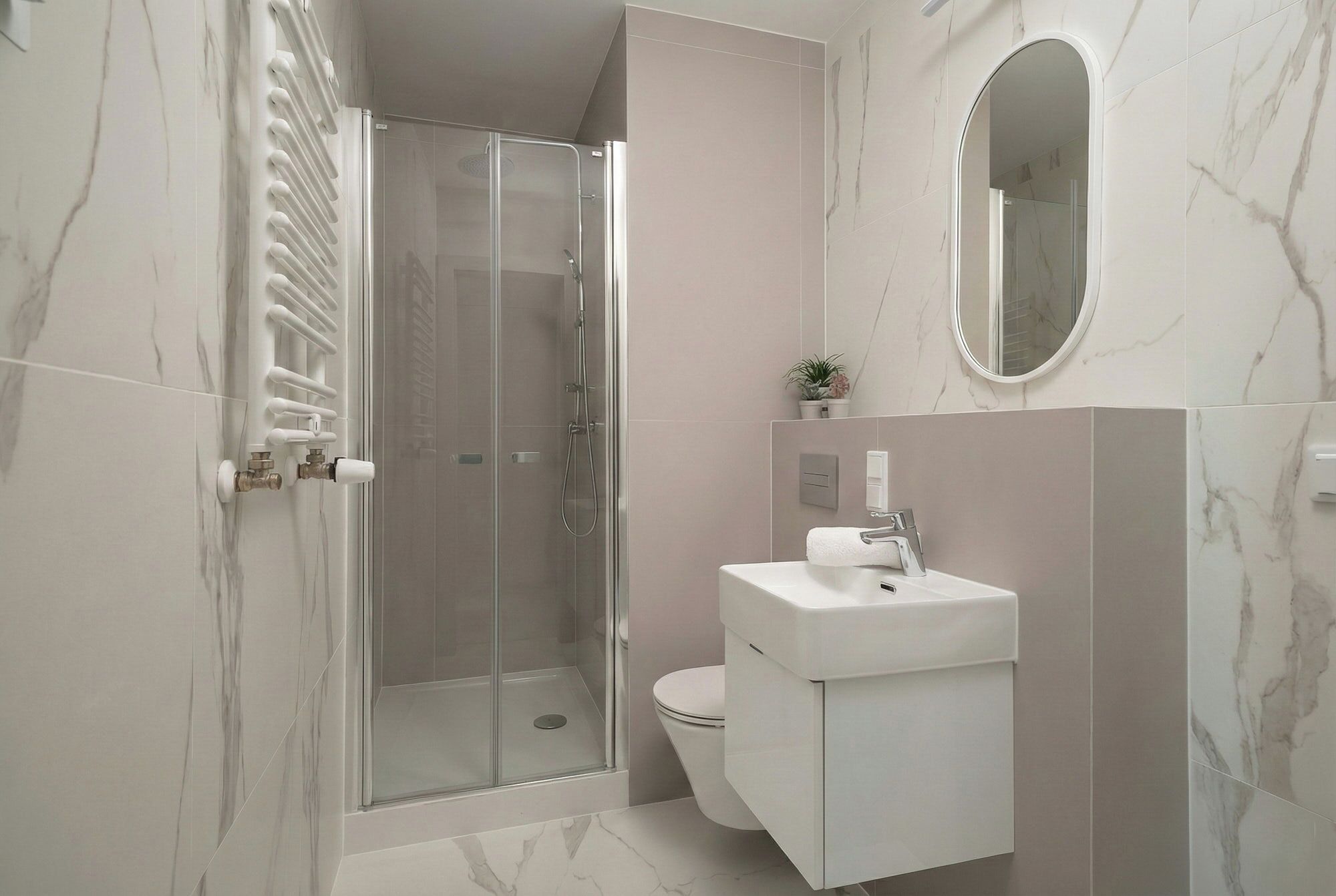 A modern bathroom with a glass-enclosed shower, a toilet, and a sink with a mirror above.
