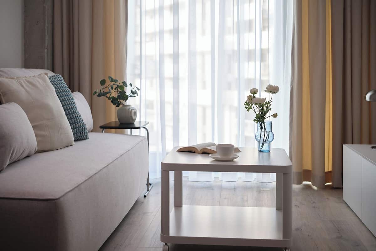Un salon moderne avec un canapé, une table basse et une petite table d’appoint sur laquelle est posé un vase de fleurs.