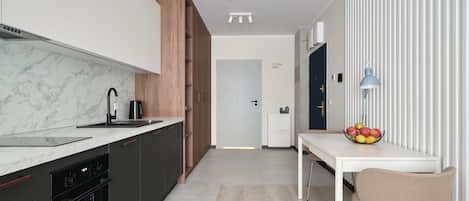 A modern kitchen with dark cabinetry, a marble countertop, and a wooden accent wall.