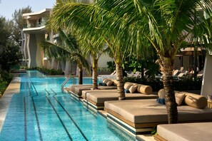 A swimming pool with lounge chairs and palm trees, surrounded by modern buildings. - Radisson Blu Resort, Phuket Mai Khao Beach (Mai Khao)