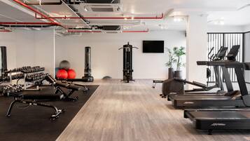 A gym with exercise equipment, a treadmill, and a wall-mounted TV.