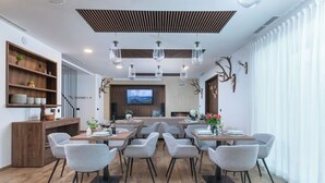 A modern dining area with multiple tables and chairs, a wooden buffet, and a television screen on the wall. - Standard Room & Spa Retreat at Resort Stribor – Relax in Nature (Severin na Kupi)