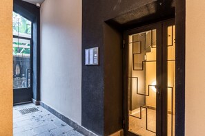 Ein Korridor mit einer Tür, deren Glas geometrische Muster aufweist, einem an der Wand befestigten Schild und einem sichtbaren Fenster.