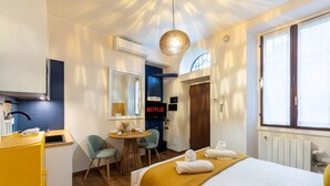 Hotelkamer met een bed, bureau, stoel, klein tafeltje met lamp, televisie en raam.