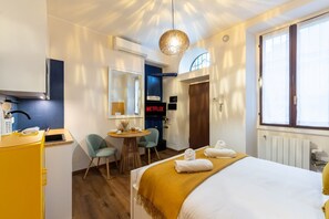 Ein Hotelzimmer mit Bett, Schreibtisch, Stuhl, kleinem Tisch mit Lampe, Fernseher und Fenster.
