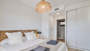 Ein Schlafzimmer mit einem Bett, Kissen, einer Nachttischlampe, einem Kleiderschrank und einer Pendelleuchte.
