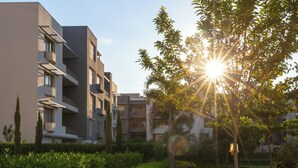 A modern apartment building with balconies and a garden area with various plants and flowers. - Luxury 3BR Serviced Apartment At Aeon Tower (6th of October City)