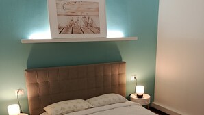 Ett sovrum med en stor säng, två sängbord med lampor, en sänggavel och en inramad tavla på väggen.