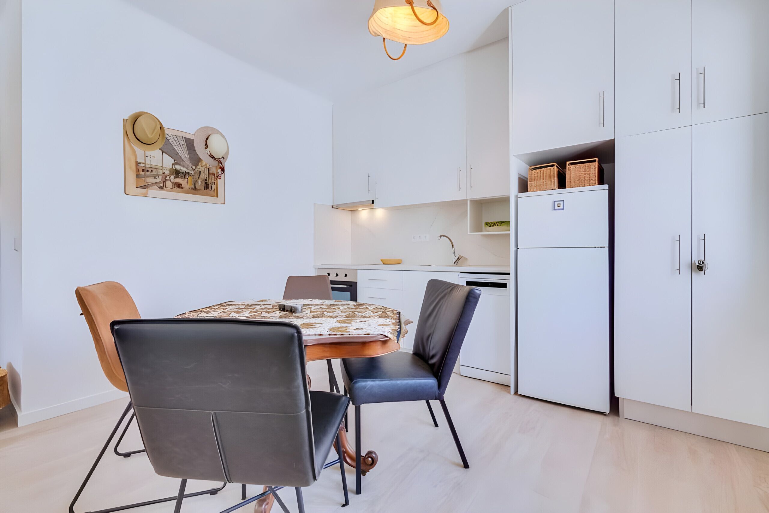Una cucina moderna con mobili bianchi, un tavolo da pranzo con sedie e una lampada a sospensione.