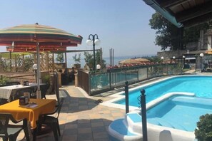 A poolside area with a pool, outdoor seating, and umbrellas. - CasaFedra:Elegant Loft on the lakefront in the Heart of the Historic Center (Toscolano Maderno)