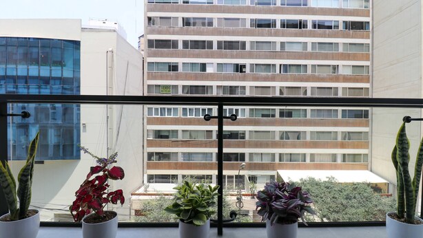 A balcony with potted plants and a view of a multi-story building with a 'VENDO' sign. - w Amazing Loft w Balcony in Miraflores (Lima)