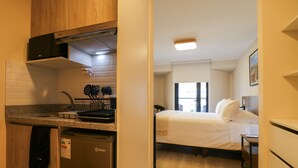 A compact hotel room with a kitchenette, a bed, and a small bedside table. - w Amazing Loft w Balcony in Miraflores (Lima)