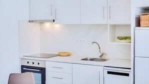 Una cocina moderna con armarios blancos, un lavamanos de acero inoxidable y un horno empotrado.