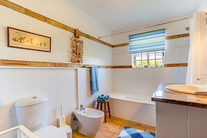 Ein modernes Badezimmer mit Toilette, Bidet, Waschbecken und Badewanne.