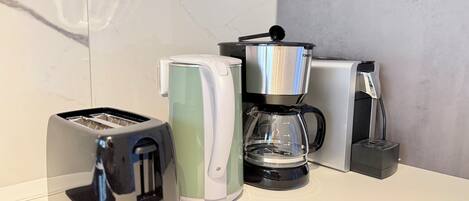 A kitchen counter with a toaster, a kettle, and a coffee maker.