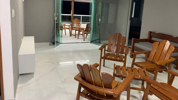 A modern interior with a glass door leading to a dining area, wooden chairs, and a white cabinet. - Modern house in Zé Pojuca / Porto de Galinhas (Ipojuca)