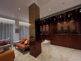 A lobby with a reception desk, seating area with sofas, and a marble floor.